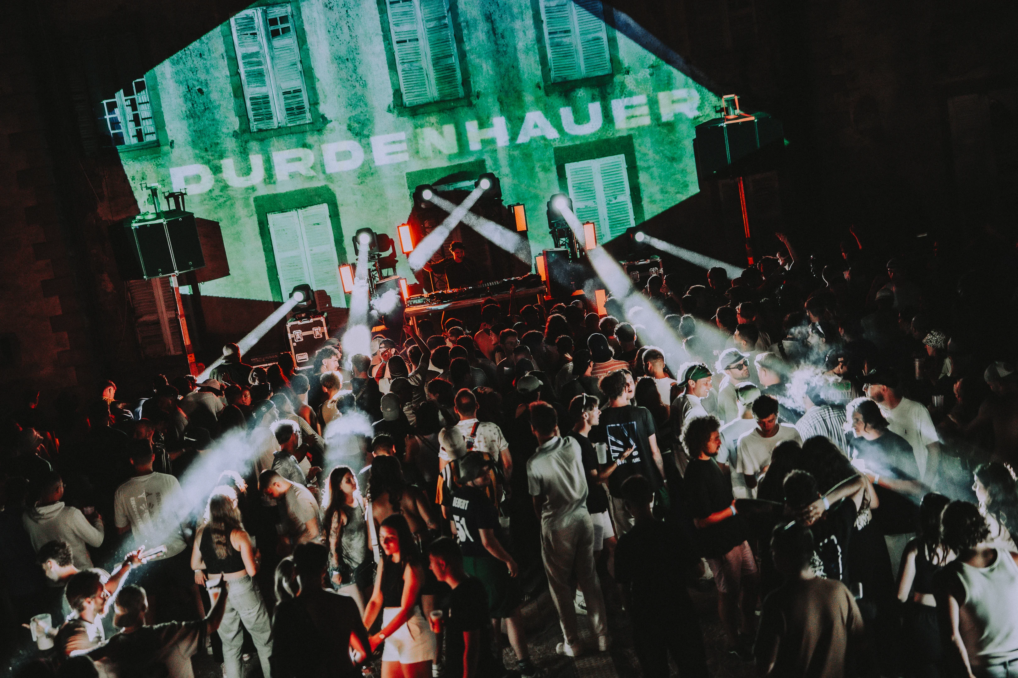 Foule dense du M2A Festival de nuit devant la scène avec le château illuminé