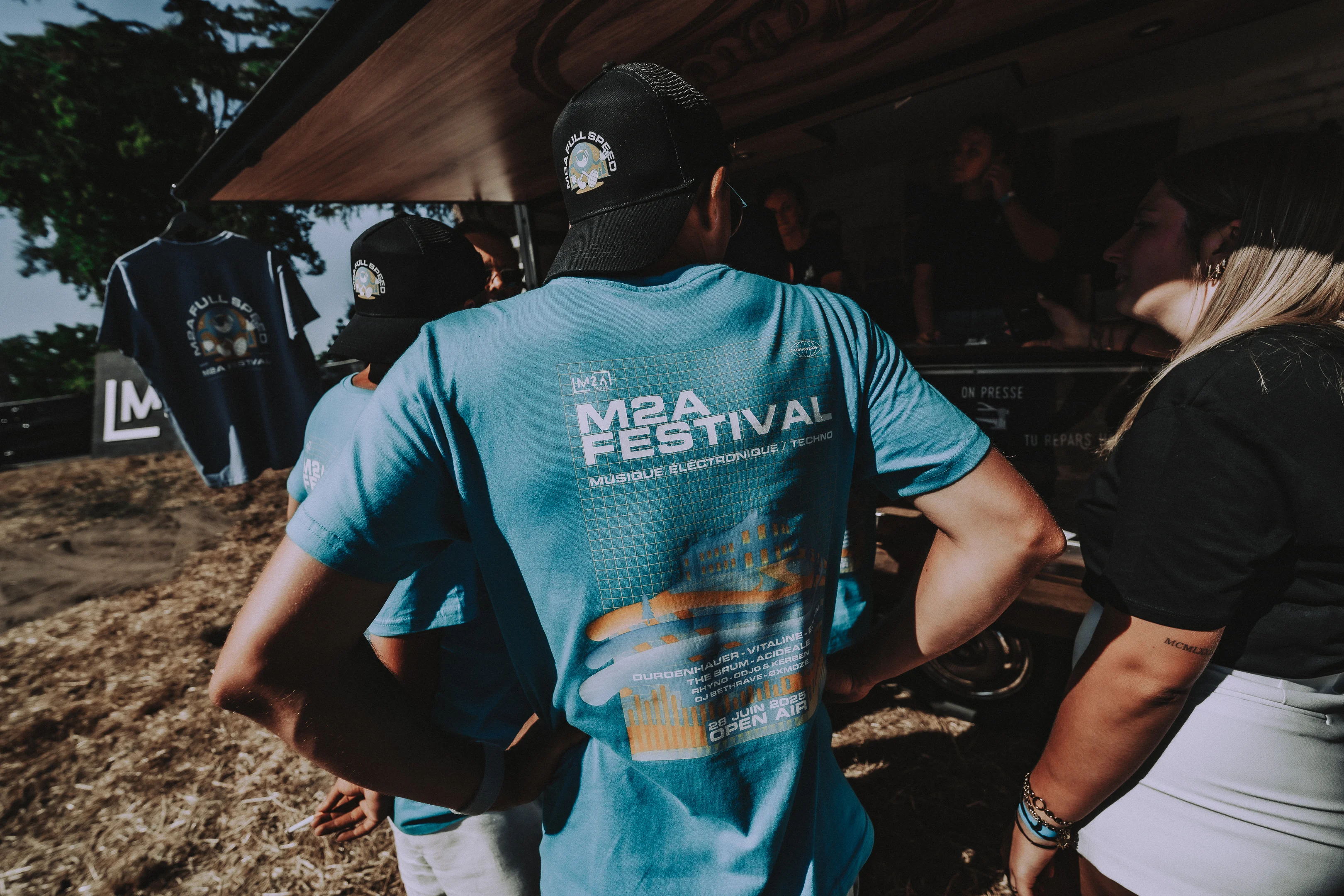 Un organisateur du M2A Festival reconnaissable à son maillot bleu, au stand de tee shirts personnalisés du festival.