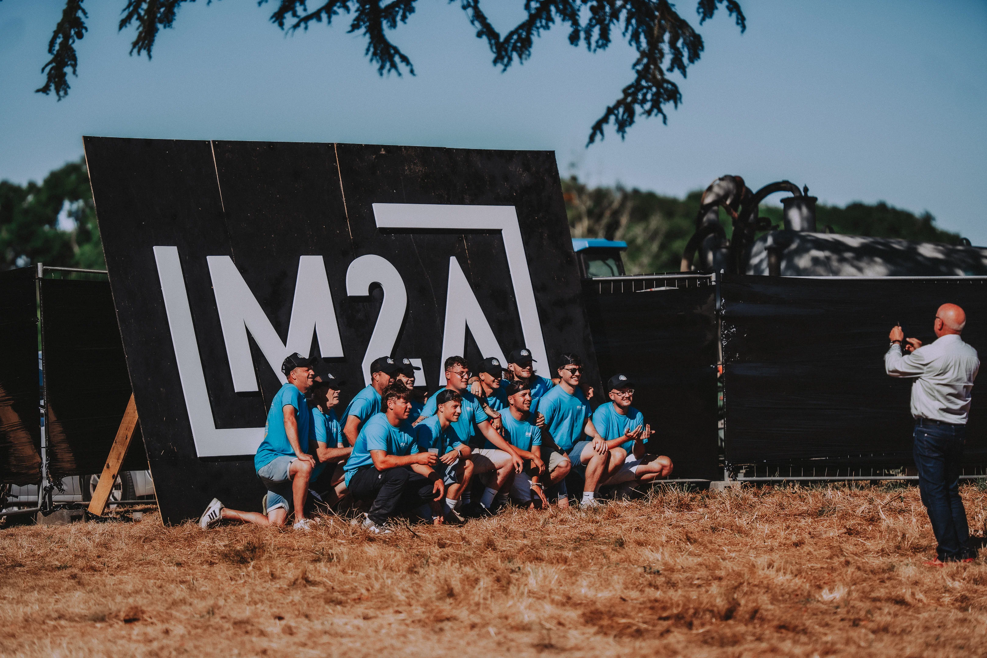 Équipe de bénévoles du M2A Festival posant devant le logo du festival