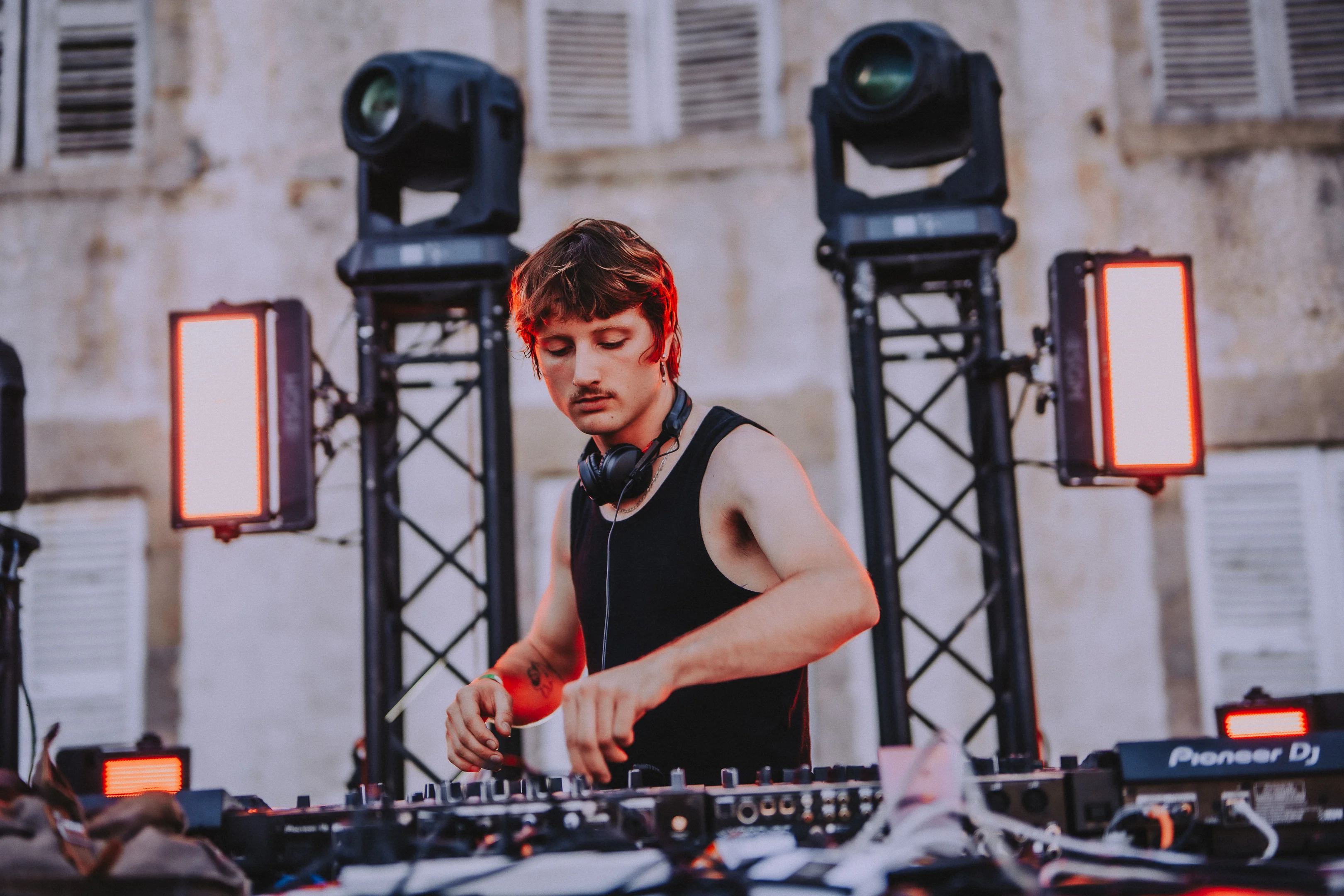 DJ en train de mixer sur la scène du M2A Festival avec éclairages scéniques