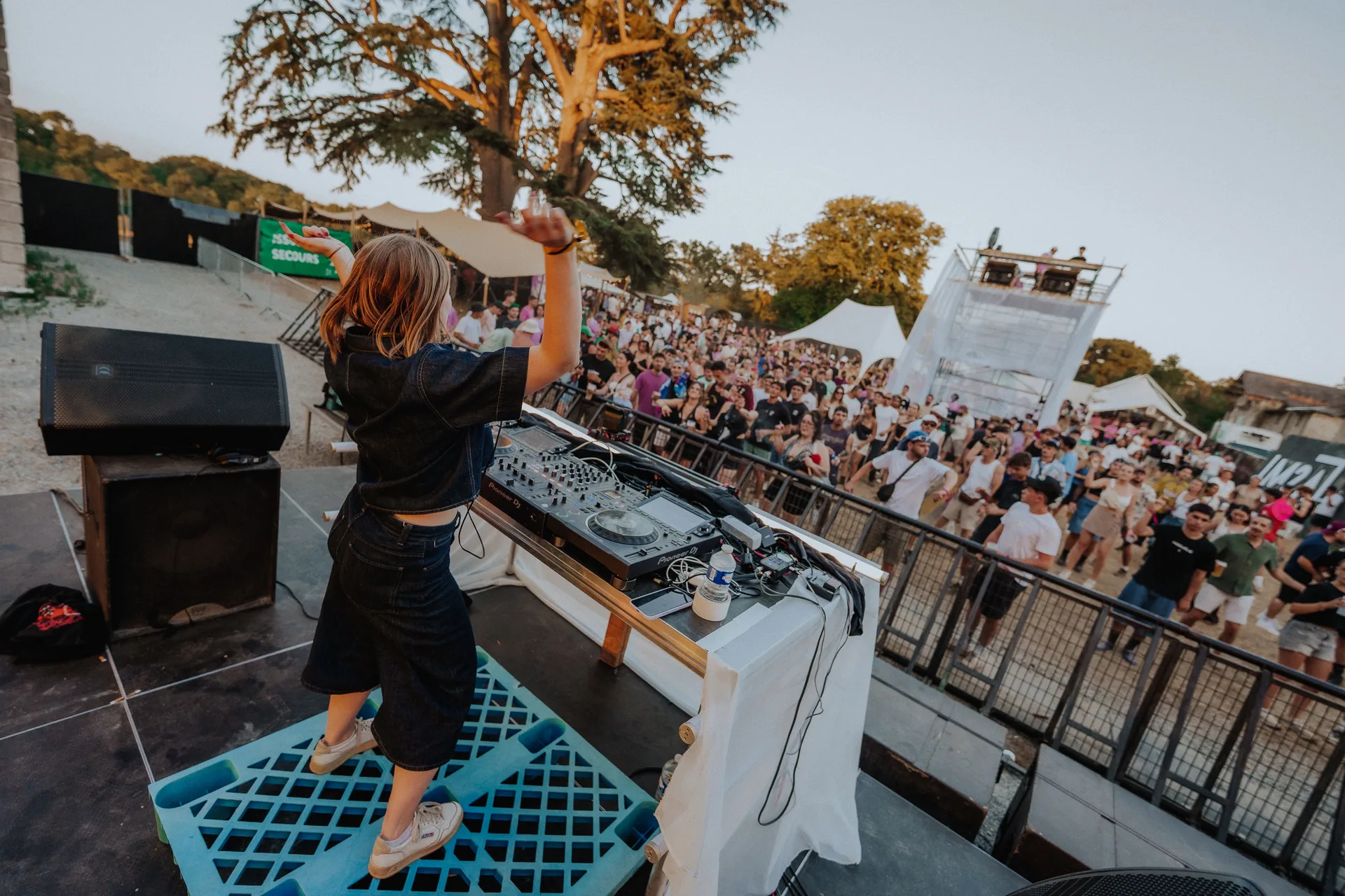 Une artiste aux platines en train de mixer devant la foule du M2A Festival
