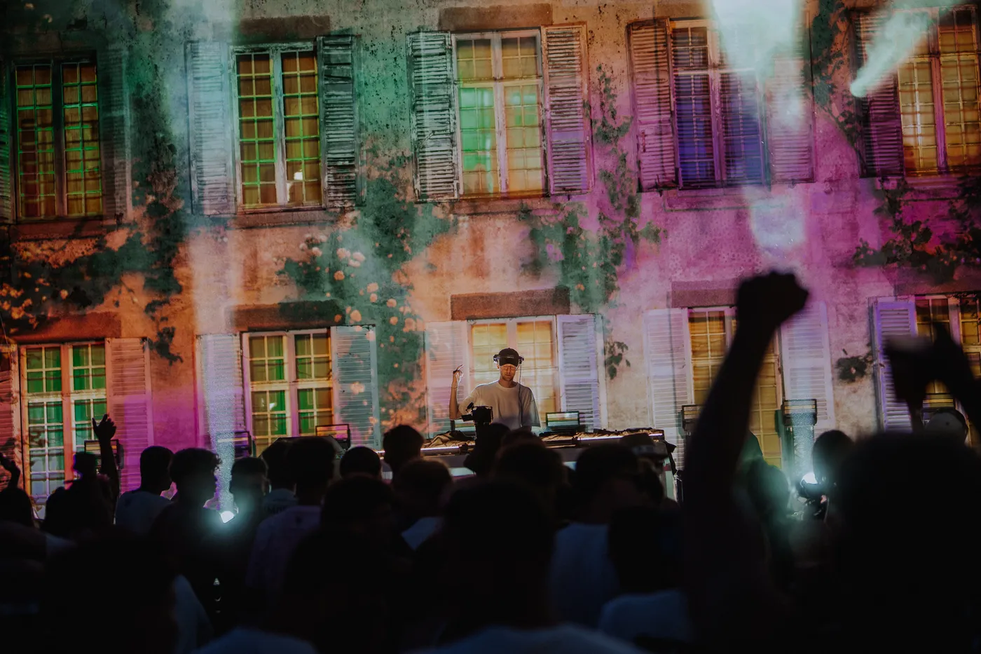 La foule du M2A Festival avec, en arrière-plan, un artiste qui mixe et le château illuminé
